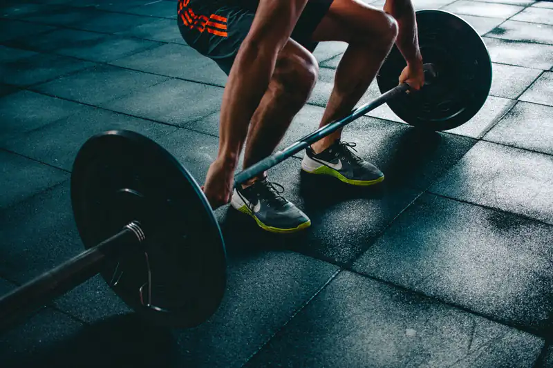 Sportovec při silovém tréninku s činkou ve FreeGym